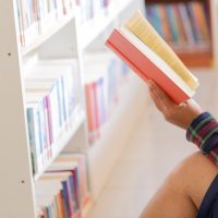Man reading. Book in his hands in library.